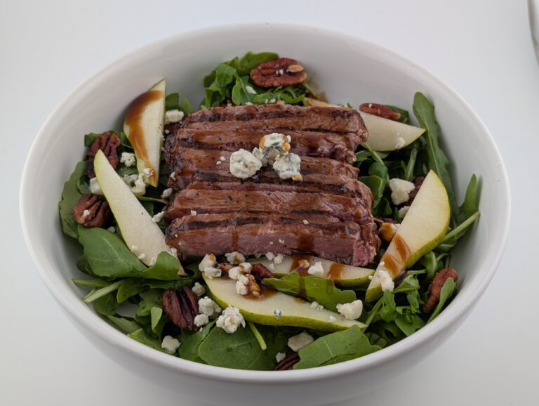 Steak slices on salad with greens